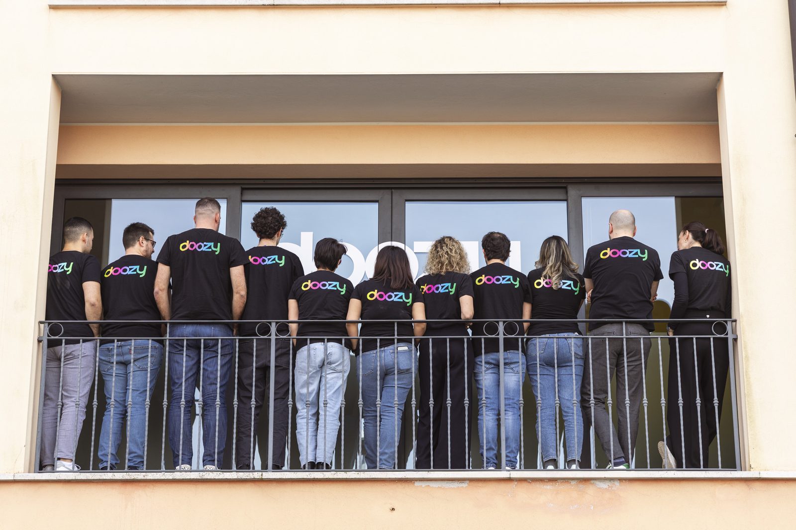 Il team Doozy di spalle sul balcone dell'ufficio con la maglietta del brand
