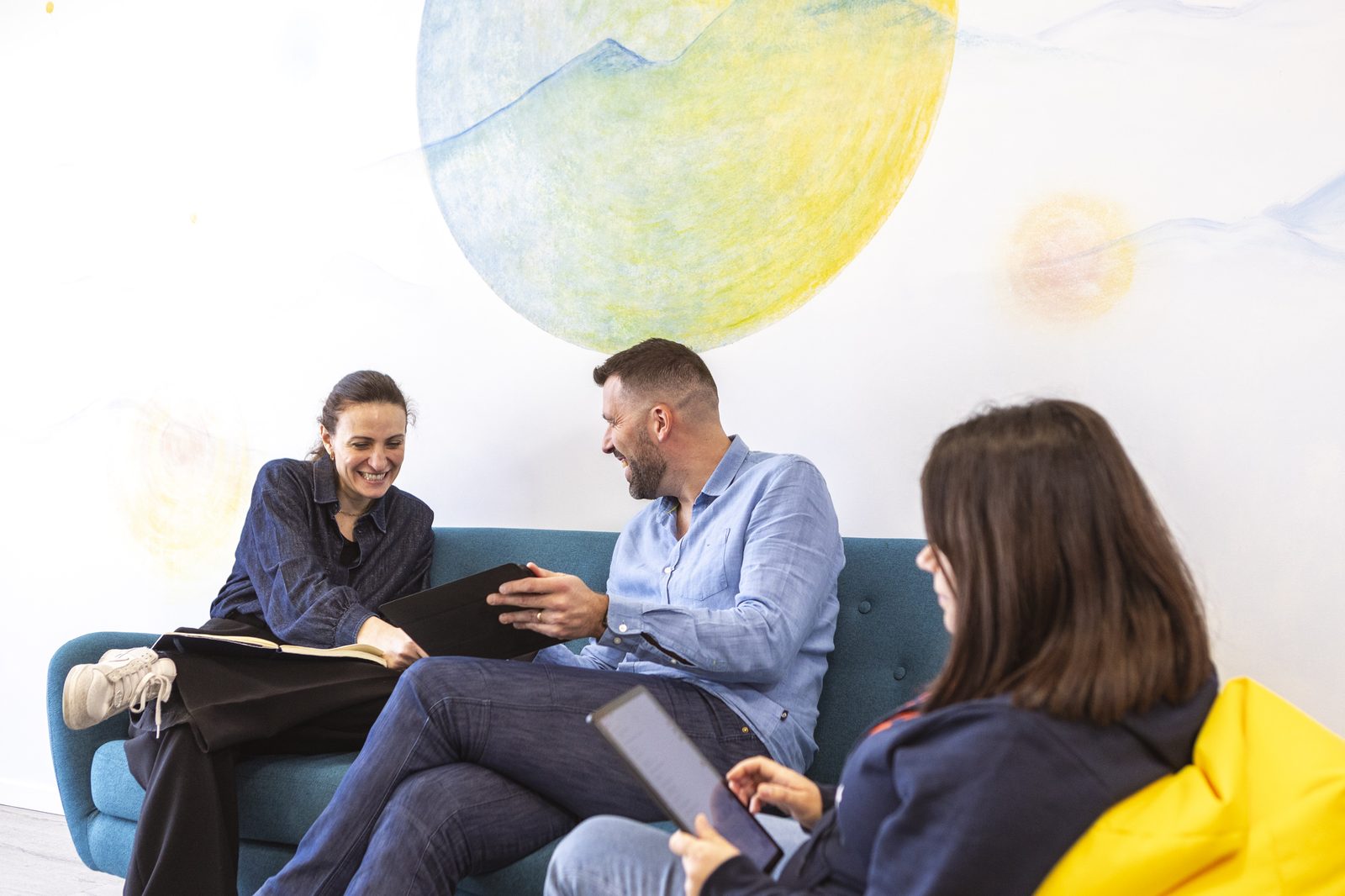Team Doozy in confronto sul divano dell'ufficio, parete con murales doozy